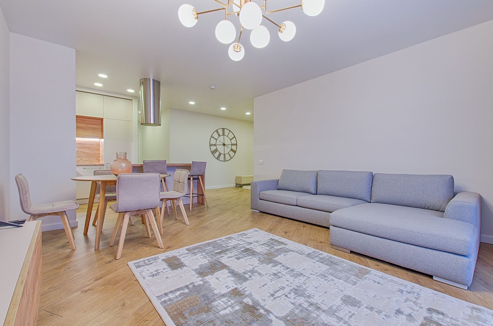 An abstract rug in front of a grey sectional sofa