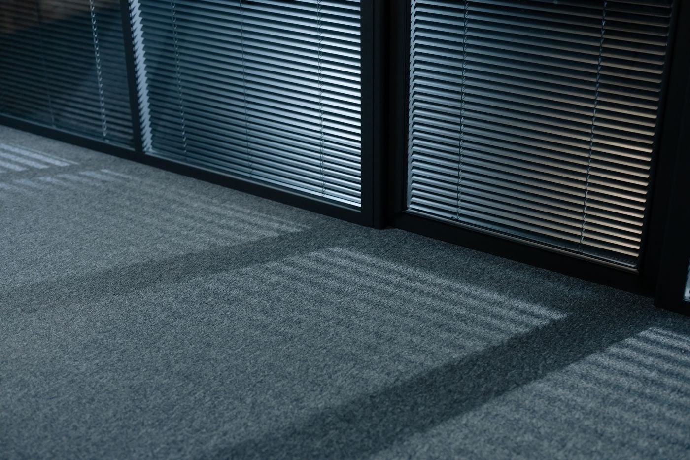 Grey wall-to-wall carpet in front of closed venetian blinds