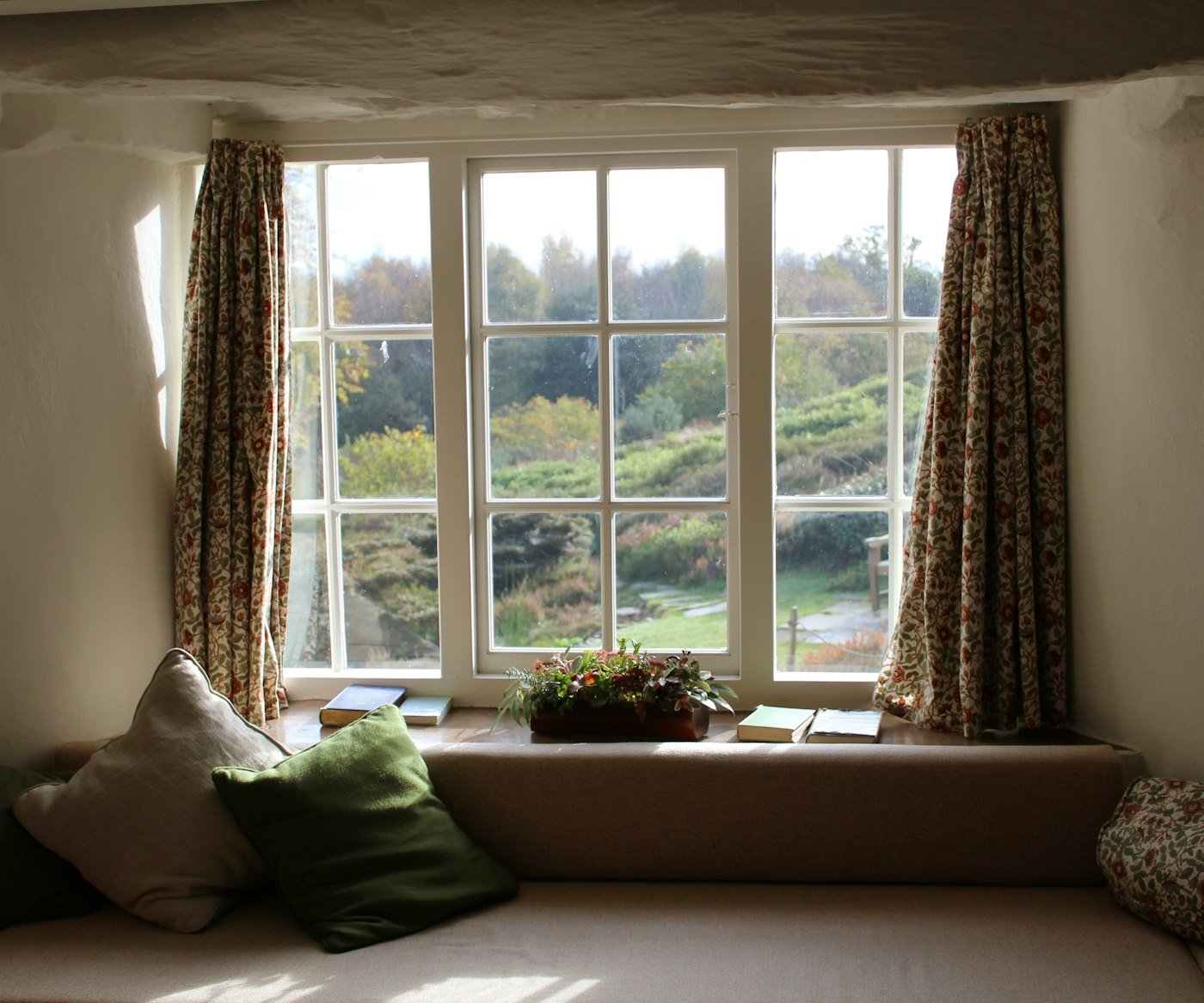 Patterned curtains drawn to either side of a window seat
